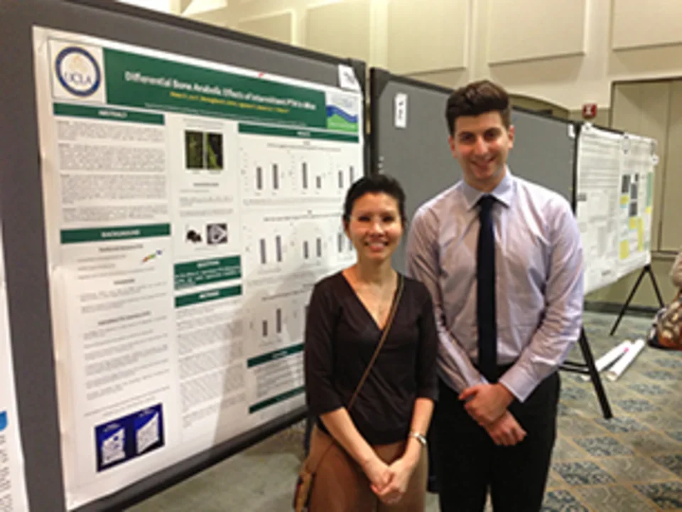 Dr. Tintut and lab member standing in front of a research poster.