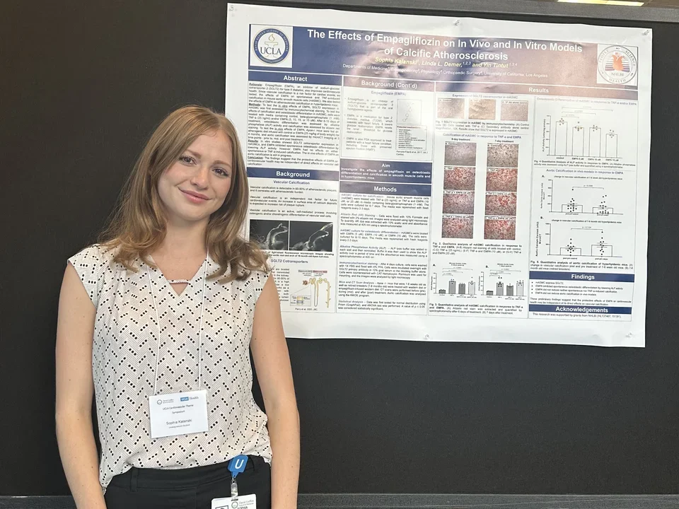 A lab member stands in front of their poster at the UCLA Cardiovascular Theme Symposium.