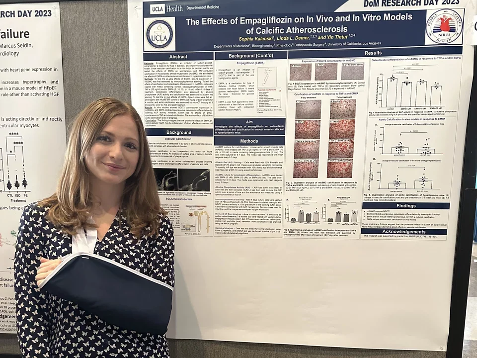 Lab member with an arm sling standing in front of a poster during UCLA DOM Research Day.